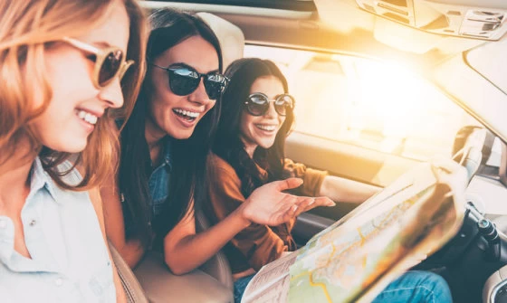 Three attractive young women going for a road trip together in their car